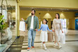 © LIGHTFIELD STUDIOS - A happy family walks through a bustling mall, carrying shopping bags and enjoying their time together.
