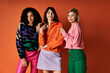 © LIGHTFIELD STUDIOS - Young beautiful women in stylish clothes pose together, celebrating cultural diversity on an orange background.