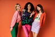 © LIGHTFIELD STUDIOS - A group of young, beautiful women in stylish, vibrant clothes standing together on an orange background, showcasing friendship and cultural diversity.