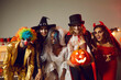 © Studio Romantic - Happy young people dressed up as different spooky characters, with scary makeup on faces having fun at Halloween costume party. Group portrait of adult friends with traditional smiley jack-o-lantern