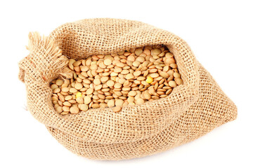 Pile of brown raw dry lentils in a rustic bag isolated on white background