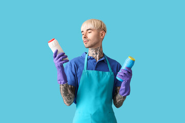 Poster - Young tattooed man with bottles of detergent on blue background