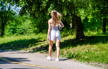 Wall Mural - Girl walks in the city summer Park
