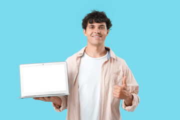 Wall Mural - Male programmer with blank laptop showing thumb-up on blue background