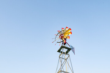 red and silver windmill on farm with blue sky