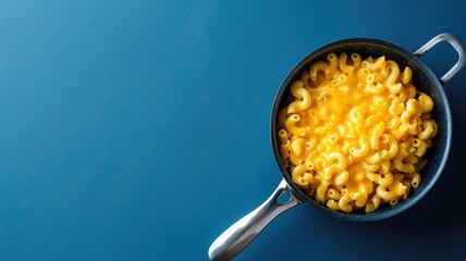 Creamy macaroni and cheese in pot on blue background