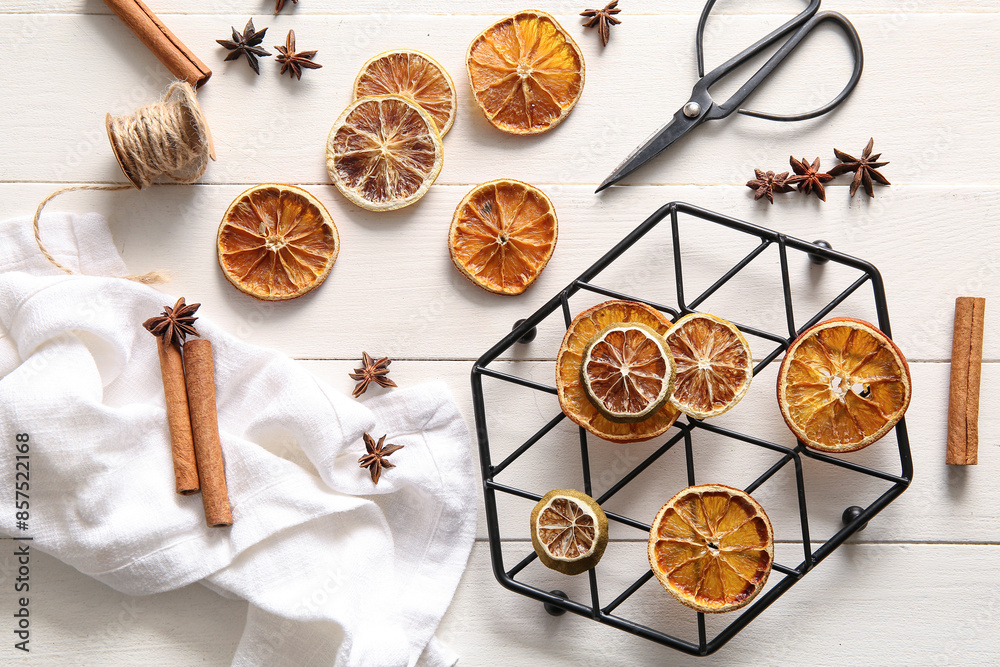 Stand with dried orange slices and cinnamon on white wooden background