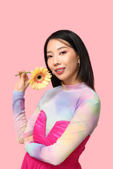 Wall Mural - Happy young Asian woman with yellow gerbera flower on pink background