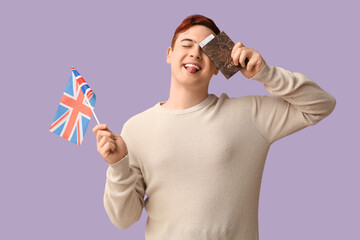 Wall Mural - Handsome young happy man with UK flag, passport and ticket on purple background