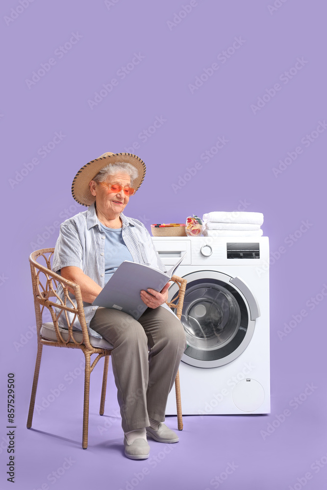 Happy senior woman with magazine resting while doing laundry on purple background