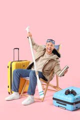 Sticker - Male tourist with suitcases, paddle and travelling accessories sitting on deck chair against pink background