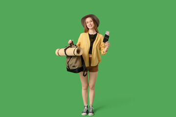 Sticker - Smiling young woman with passport and backpack on green background. Travel concept