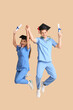 © Pixel-Shot - Happy medical graduate couple with diplomas and stethoscopes near beige wall