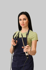 Wall Mural - Female hairdresser with iron and tongs for hair extension on light background