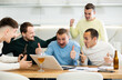 © JackF - Excited friends gathered around laptop, celebrating successful investment made through online platform at casual home meeting with beer