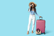 © Pixel-Shot - Happy young African-American woman with suitcase and camera on blue background