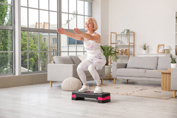 Sticker - Sporty beautiful mature happy woman training with aerobic stepper at home