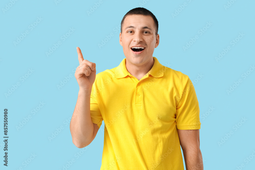 Handsome young shocked man pointing at something on blue background