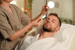 © Pixel-Shot - Handsome young man receiving facial massage with serum in beauty salon