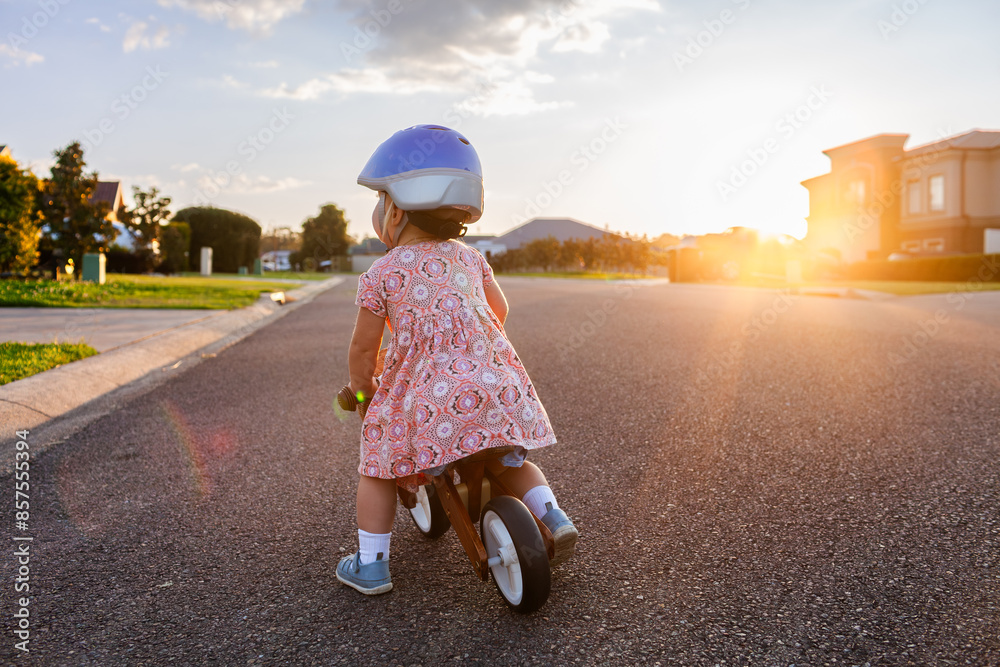 Kid riding balance bike down quiet suburban road wearing helmet in ...