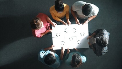 Sticker - Top down view of business people gathering jigsaw together at meeting. Aerial view of diverse team collect or put piece of jigsaw puzzle together and standing while wearing casual cloth. Symposium.