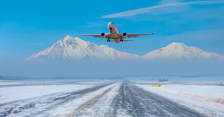 Wall Mural - Passenger airplane fly up over take-off runway snowy mountains in the background - Snow-covered airport