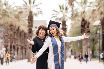 Wall Mural - Excited mother and graduate daughter on graduation day with palm