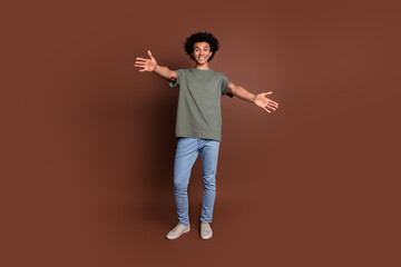 Canvas Print - Full body length photo of youth guy with wavy hair in gray t shirt and jeans casual garment friendly hugs for you isolated on brown color background