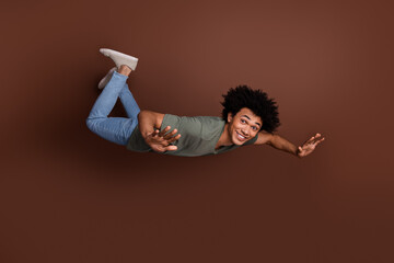 Canvas Print - Full body photo of attractive young man falling down flying dressed stylish khaki clothes isolated on brown color background