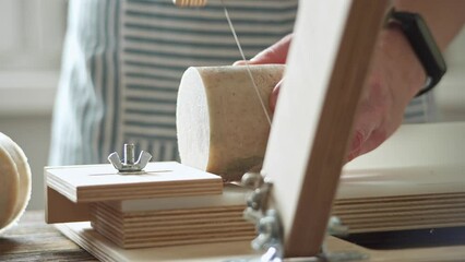 Wall Mural - Soap maker cuts a round handmade soap on a wooden cutter. Home production of natural cosmetics