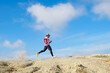 © STOCK PHOTO 4 U - Man Running on a Rocky Trail Under a Clear Blue Sky with White Clouds in the Background