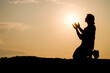 © STOCK PHOTO 4 U - Silhouette of a Person Praying at Sunset with Hands Raised Towards the Sun in a Peaceful Outdoor Setting