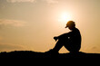 © STOCK PHOTO 4 U - Silhouette of a Person Sitting on a Hill at Sunset with a Golden Sky in the Background