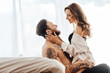 © Maria Vitkovska - Happy sexy young couple embracing and kissing sitting on the floor leaning against the bed