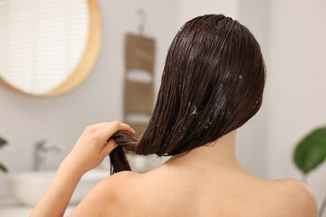 Poster - Woman applying hair mask in bathroom, back view