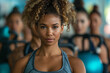 © apichat - Focused young woman in a fitness class holding a heavy kettlebell overhead, showing strength and determination.