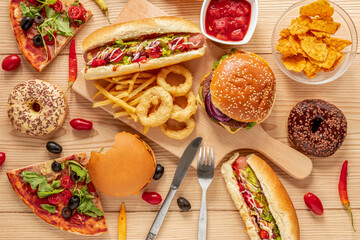 Wall Mural - A tempting overhead view of a delicious food frame, featuring classic favorites like burgers and pizza alongside fries, toast, and a donut. Perfect for a fun and indulgent menu or advertisement. 