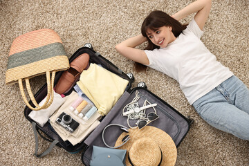 Canvas Print - Woman packing suitcase for trip on floor indoors, top view