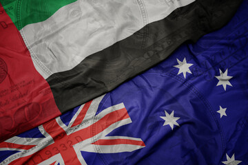 waving colorful flag of united arab emirates and national flag of australia on the dollar money background. finance concept.