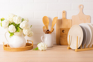 Wall Mural - A beautiful kitchen backdrop with various kitchen utensils and a jug with flowering branches. still life. Front view