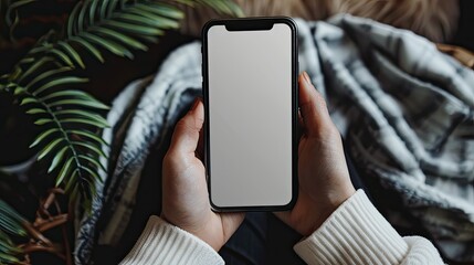 Close-up of adult hands gripping a smartphone, blank screen visible