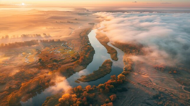Aerial photography of a beautiful river bend amid low clouds at autumn sunrise in Ukraine. The turning of the river Meadows and fields, grass, orange trees, golden sunlight at dawn in autumn.