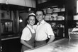 © HNJ - Vintage black and white photo of a friendly young couple owners of an Napolitan pizza shop, 1950s.