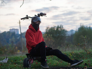 Wall Mural - A young man rides a scooter in autumn. Wearing a helmet and balaclava