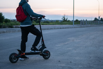 Wall Mural - a young man on an electric scooter rides around the city