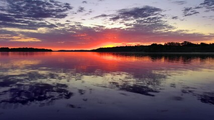 Wall Mural - Perfect red dawn sky reflected in tranquil waters, then rising-up to meet the sunrise.
