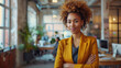 © Neat Design Studio - Portrait of a young confident black African American woman wearing a yellow jacket and standing in a modern open-space of a startup or tech company with space for text