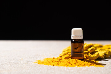 Turmeric essential oil on black and gray stone background, space for text.
