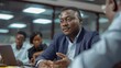 © Intelligent Horizons - African male professional businessman in a meeting room giving feedback and discussing strategy with his diverse team of coworkers during a collaborative brainstorming session