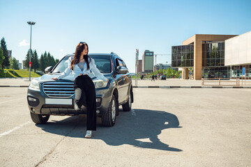 Wall Mural - A girl stands by a car on a sunny summer day.